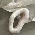 Close-up of white plush cloud hair claw clip with soft lamb wool texture on stone surface - White