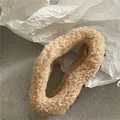 Primer plano de pinza para el pelo de felpa camel con cuentas oscuras sobre fondo mármol - Caqui