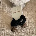 Detailweergave van zwarte elastische haarelastiekjes met schattige luipaardprint pomponbedels - Zwart