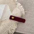 Makroaufnahme einer weinroten Samt-Haarspange mit kleinem goldenem Herz auf weißem Stoff - Herz Rechteck BB Clip / Rot