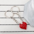 Detailed view of silver metal interlocking heart keychains with red enamel finish - Red Pair