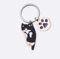 Detail van een creatieve katten-sleutelhanger met gouden ring en emaille kattenpootjes - Koe Kat
