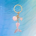 Sparkly mermaid tail keychain with pink starfish and shell charm on blue wavy background - Pink Fish Tail