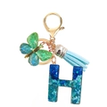 Close-up of blue sequin resin letter H keychain with butterfly and tassel details - Letter H