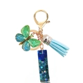 Detail of blue sequin resin pillar, soft butterfly charm and light blue tassel keychain - Letter I