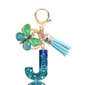 Detail of resin letter J keychain with blue sequins, butterfly charm, and leather tassel - Letter J