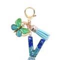 Detailed close-up of a resin letter V keychain with blue sequins and teal suede tassel - Letter V