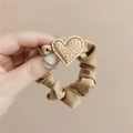 Detalle de coletero caqui con un colgante de corazón martillado y borde dorado - Marrón
