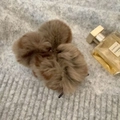 Detalle de pinza de pelo de felpa marrón sobre suéter de punto gris con perfume - Marrón