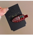 Détail d'une pince à cheveux à carreaux rouges avec des breloques cerise sur une carte - Bordeaux