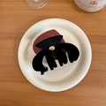 Detail of classic black velvet hair claw clip with golden metal logo on a ceramic plate - Pumpkin Claw Clip (D-4931-2)