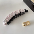 Close-up of a floral satin banana hair clip and gold hoop earrings on a white surface - Black with Pink Floral