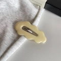 Minimalistische wellenförmige Haarklammer in Creme auf grauem Stoff für einen modernen Look - Beige