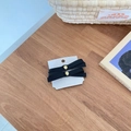Detail view of two black satin bow hair clips with gold metal buckles on a white display card - Grosgrain Ribbon Bow (D-5136-4) / Black