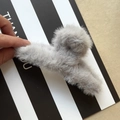 Elegante pinza de pelo de felpa gris para mujer presentada sobre un fondo a rayas - Gris
