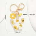 Détail du porte-clés en résine lettre W avec fleurs séchées jaunes et pendentif abeille - Style Lettre W