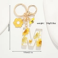 Détail du porte-clés lettre M en résine avec fleurs séchées jaunes et mesures du produit - Style Lettre M