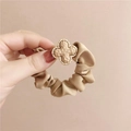 Beige scrunchie with a gold hammered clover charm held in hand for size display - Hammered Texture Clover / Brown