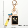 Detailed view of golden keychain with letter L, blue butterfly and yellow tassel - L