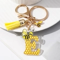 Detail of letter E keychain with yellow honeycomb pattern, bee charm and leather tassel - Letter E