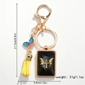 Detail view of golden butterfly keychain with blue-pink charm and letter T pendant - Letter T