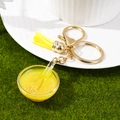 Miniatuur voedselschaal sleutelhanger met gele pap, kwastje en gouden metalen ring - Gierstpap
