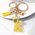 Close-up of letter K keychain with yellow honeycomb pattern and bee tassel charm - Letter K