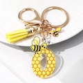 Detail of acrylic letter O keychain with honeycomb pattern and yellow fiber tassel charm - Letter O