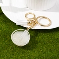 Close-up of a realistic miniature white porridge bowl keychain with golden hardware - Rice Porridge