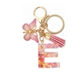 Close-up of resin letter E keychain with pink sequins, butterfly charm and tassel details - Letter E