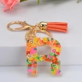 Détail du porte-clés lettre R en résine avec tranches de fruits et pompon orange - Lettre R