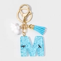 Detail of blue resin letter M keychain featuring white clouds and a blue silk tassel - Letter M Style (M)