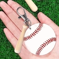 Llavero de béisbol con bate de madera y pelota blanca sostenido en la mano sobre césped - Estilo Béisbol Blanco Y Bate (2)