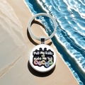 Detail of metal bingo ball keychain with humorous slogan on beige stone near blue water - Pull My Balls And Make Me Yell Bingo(4)