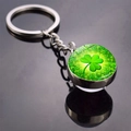 Close-up of four-leaf clover keychain with double-sided glass orb on reflective surface - Radial Green Light Clover(10)