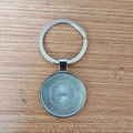 Silver metal keychain with geometric mandala weave pendant on a light wood background - Mandala Woven Texture DIY Metal Base Style