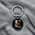 Close-up of metal keychain featuring letter E with floral pattern on grey plush background - Letter E