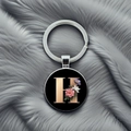 Close-up of letter H keychain with floral design on a soft textured grey background - Letter H