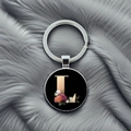 Macro detail of silver keychain featuring a black glass dome with a gold letter L and flowers - L