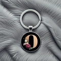 Close-up of alphabet letter O glass dome keychain with elegant floral pattern over grey fur - Letter O
