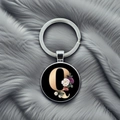 Close-up of circular metal keychain with golden letter Q and elegant floral art on gray fur - Letter Q