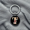 Detailed view of metal keychain featuring a black round pendant with floral letter T design - Letter T