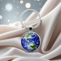 Detail of Earth planet pendant on a silver keychain with crystal dome and silk background - Earth