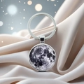 Detailed close-up of a moon texture keychain with craters on a silky fabric background - Moon