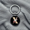 Close-up of silver keychain with letter X and floral patterns on black background - Letter X