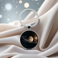Macro shot of a silver Saturn planet pendant on soft silk background with bokeh lighting - Saturn