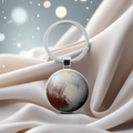 Macro detail of planet Pluto crystal glass keychain on luxury champagne silk fabric - Pluto