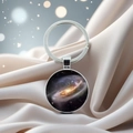 Macro shot of silver galaxy pendant keychain featuring a celestial nebula on silk fabric - Milky Way