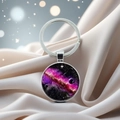 Close-up of galaxy crystal keychain on beige satin with dreamy bokeh lighting effects - Neon Sea