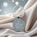 Detail view of silver bible quote keychain with floral design on soft silk background - Luke 18:1(5)